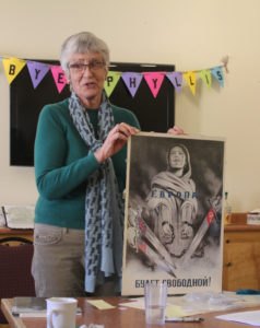 A woman holding up an image of a person with pencils.