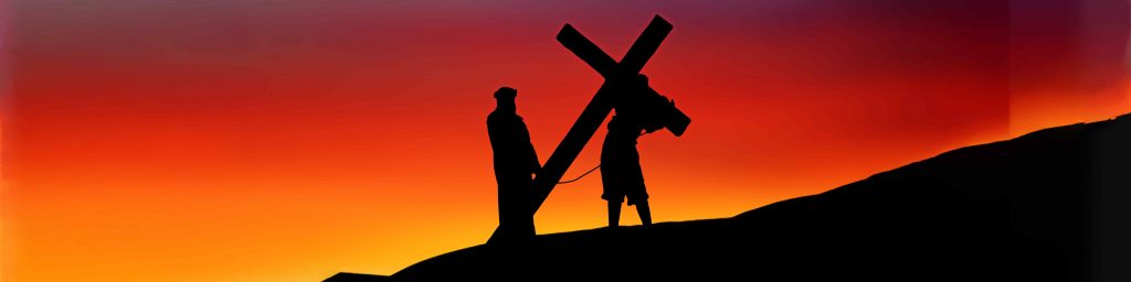 A person holding onto a cross while standing on top of a hill.